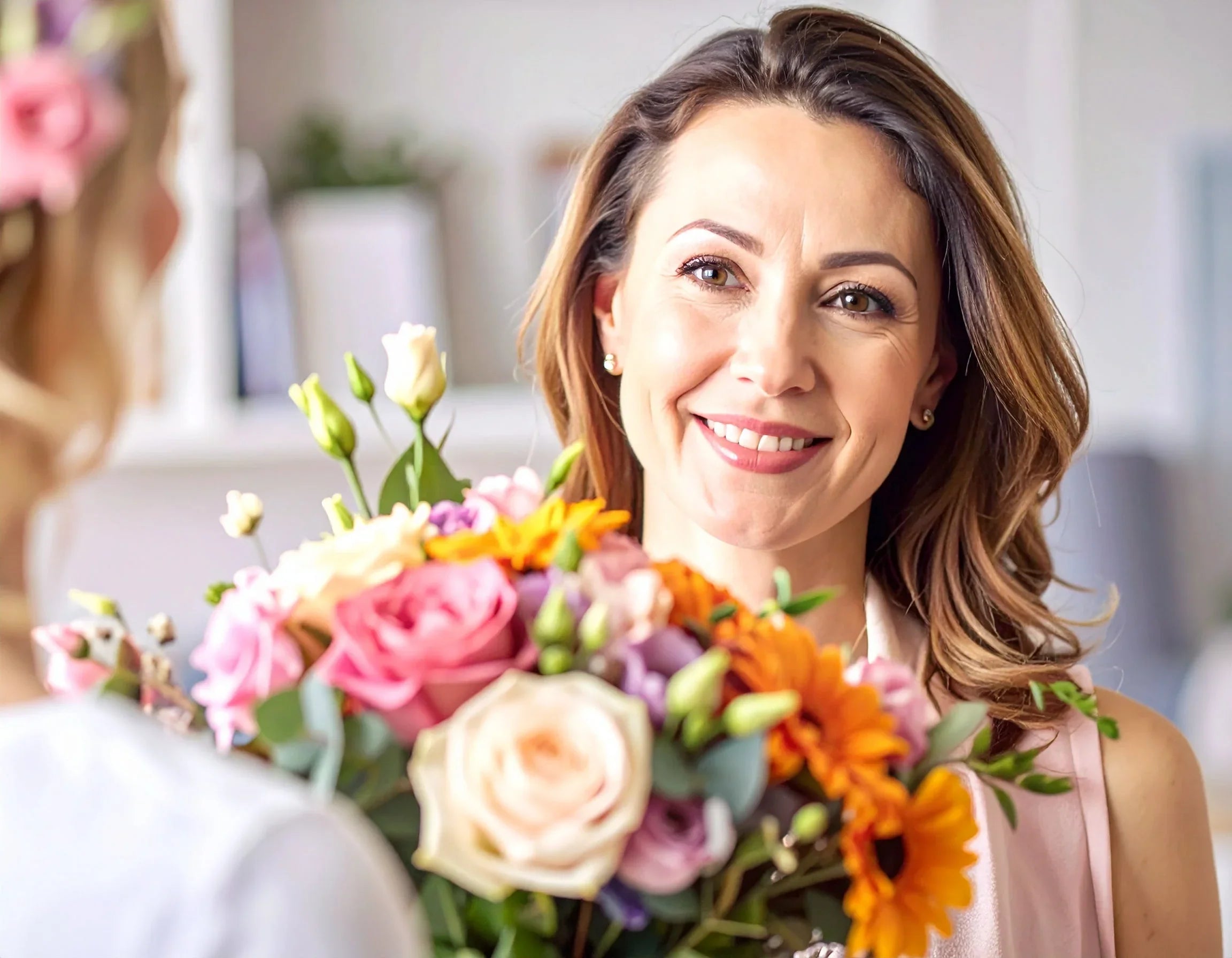 Lächelnde Frau mit buntem Blumenstrauß aus Rosen und Sonnenblumen – frische Blumen geschenken