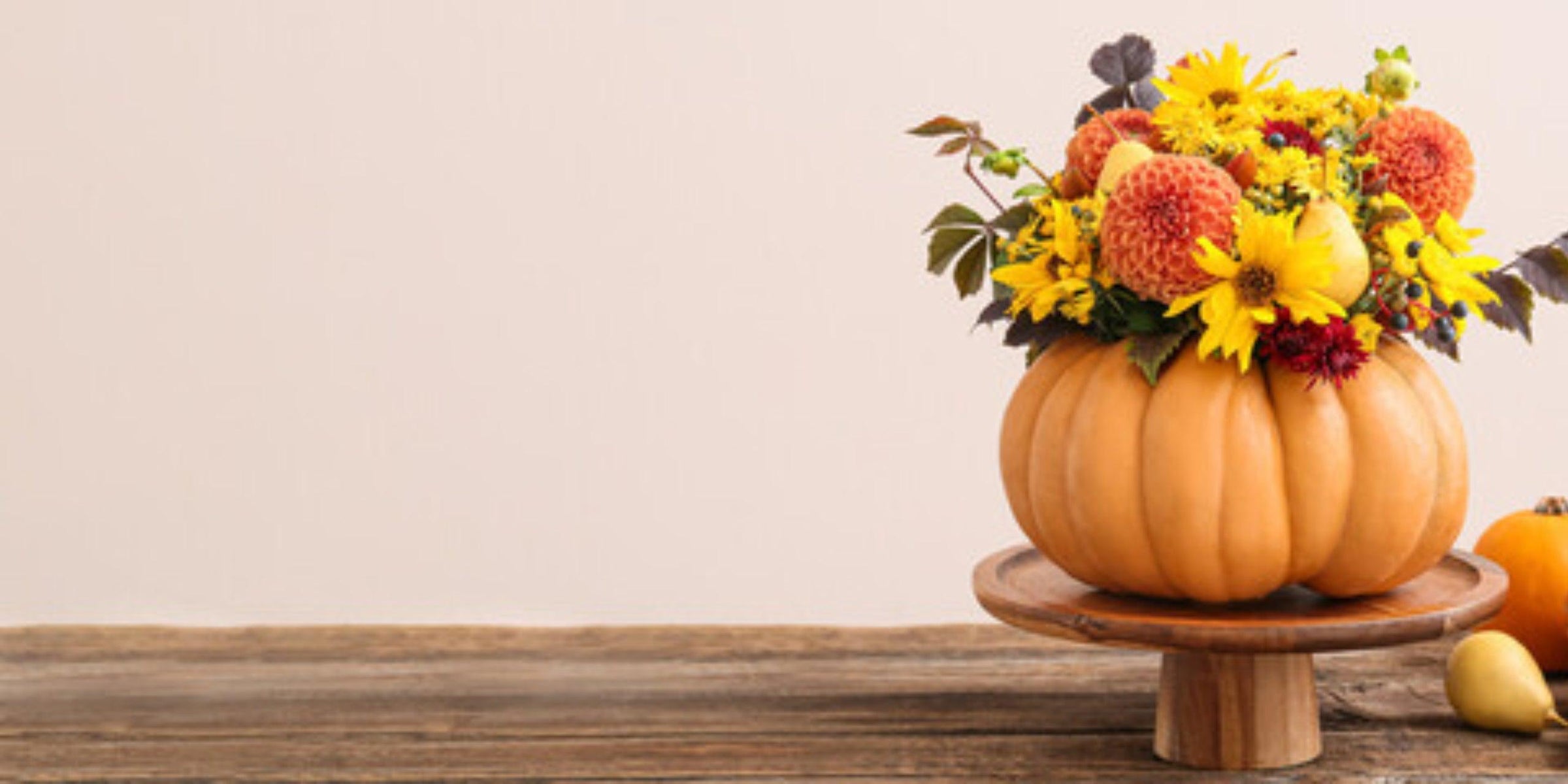 Herbstlicher Blumenstrauß mit Kürbis, Sonnenblumen und Birnen auf Holztablett