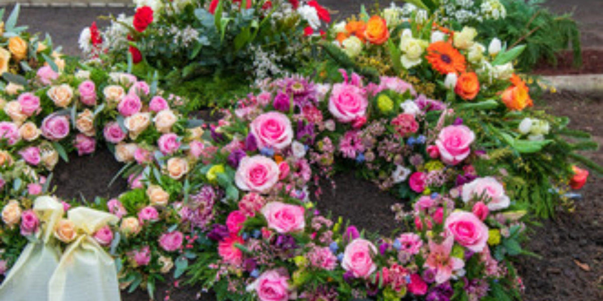 Bunte Blumenkränze mit Rosen und Gerbera, frisch arrangiert für Trauerfeiern