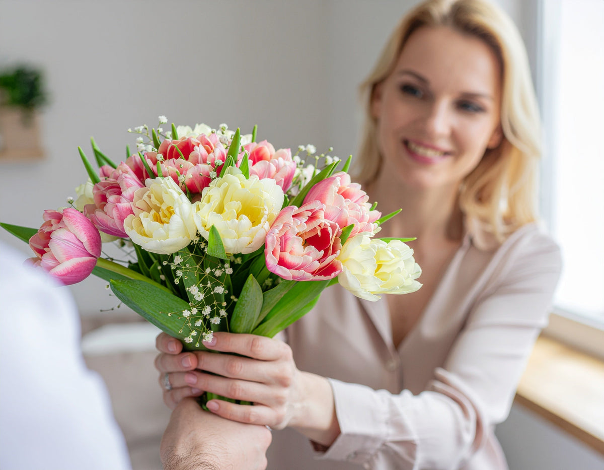 Frau erhält frischen Tulpenstrauß in Rosa und Cremeweiß – perfekt als Geschenk oder zur Dekoration