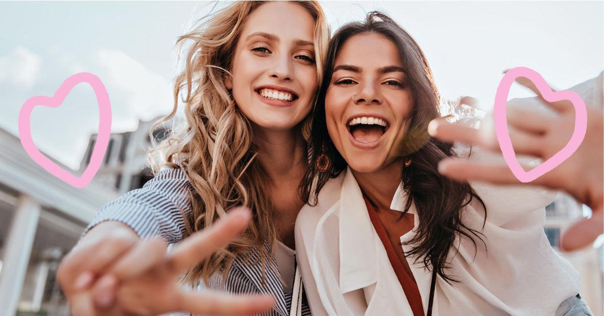 Zwei lächelnde Frauen machen Selfie mit Herz-Gesten – perfekt für Blumensträuße & Geschenke