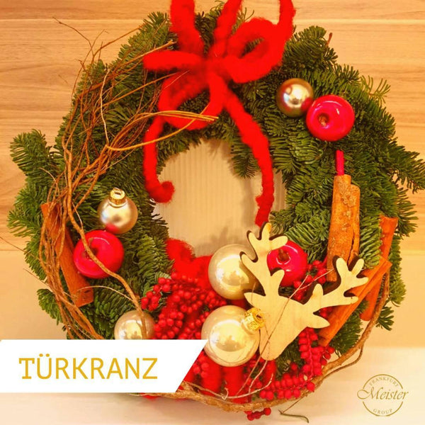 Weihnachtlicher Türkrantz mit Tannenzweigen, rotem Band, Kugeln, Zimtstangen und Rentier-Dekoration