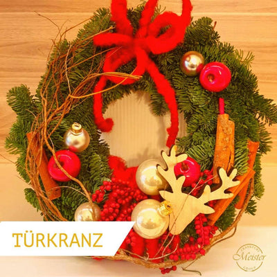 Weihnachtlicher Türkrantz mit Tannenzweigen, rotem Band, Kugeln, Zimtstangen und Rentier-Dekoration