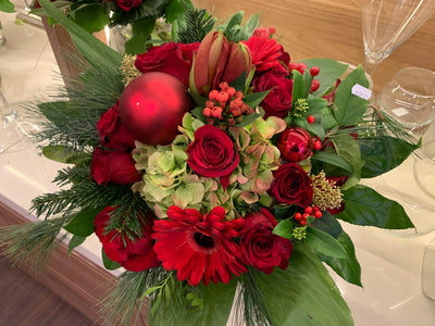 Festlicher Weihnachtsblumenstrauß mit roten Rosen, Gerbera, Tannenzweigen und roten Kugeln
